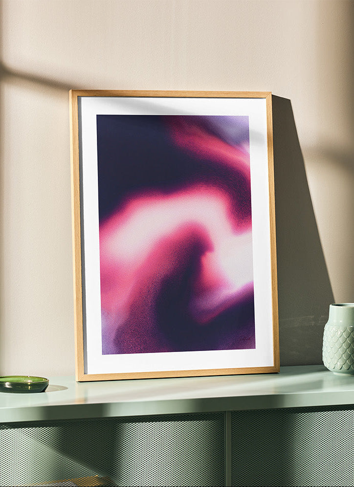 Framed contemporary abstract artwork "Becoming" from the Infinite Studio series by Nicole Potrich featuring magenta and black fluid marble-inspired abstraction symbolising transformation and emergence, on top of teal furniture.